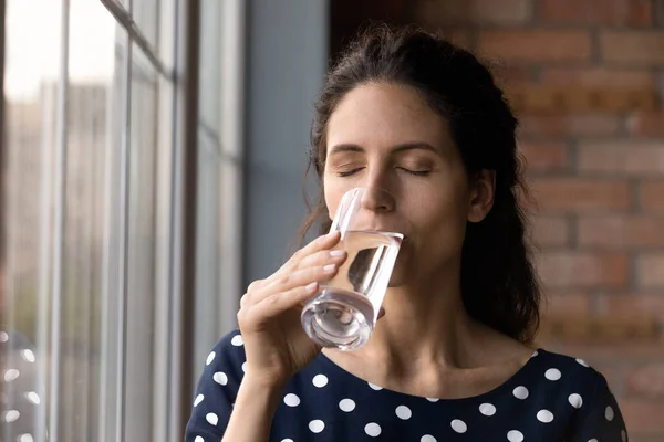 Mujer hispana joven pacífica bebiendo vaso de agua dulce pura. — Foto de Stock