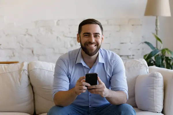 Portret van een lachende jongeman met smartphone in handen. — Stockfoto
