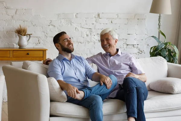 Glücklicher junger Mann kommuniziert mit pensioniertem Vater. — Stockfoto