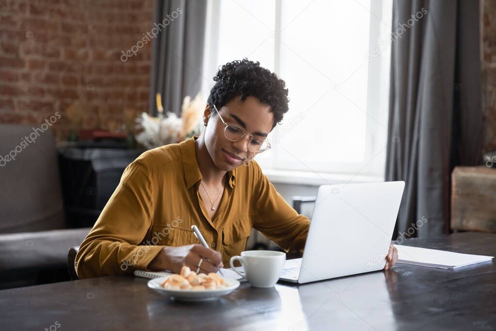 Happy smart young African American woman studying at home.