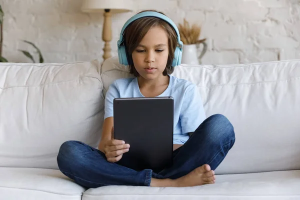 Happy little teenage boy in headphones using tablet. — 图库照片