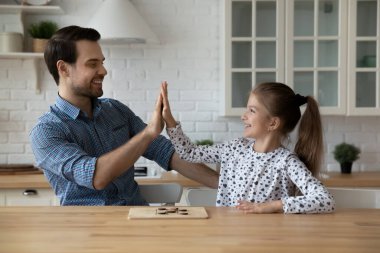 Mutlu baba ve kız beşlik çakıyor, masa oyunu oynuyorlar.