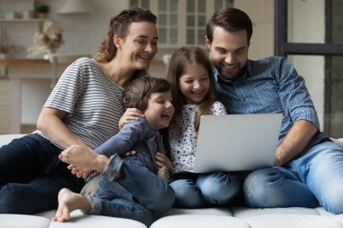 Evde dizüstü bilgisayar kullanan iki çocuklu mutlu bir aile.