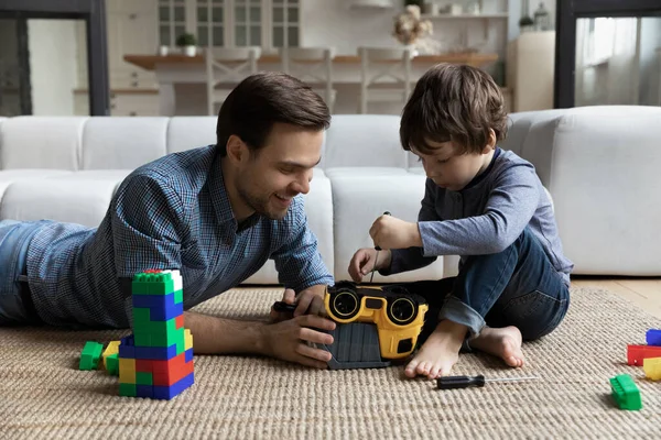 Little son repairing toy car with loving father, using screwdriver — Foto Stock