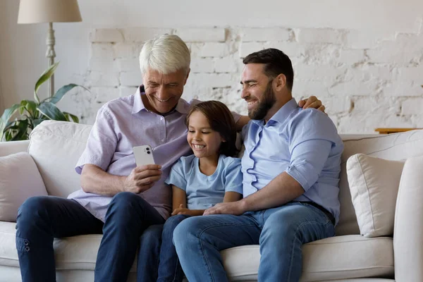 Šťastné tři mužské generace rodina pomocí mobilní aplikace doma. — Stock fotografie