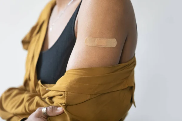 Nahaufnahme aufgeklebtes Pflaster auf dem Arm einer jungen Afroamerikanerin. — Stockfoto