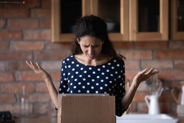 Unhappy anxious young latin woman unboxing carton parcel. — Foto Stock