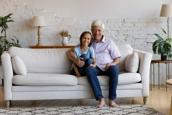 Happy old grandfather and preteen kid resting on couch. — Stock Photo, Image