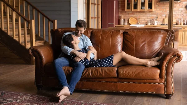 Tillgiven glad ung familj par koppla av på mysig soffa. — Stockfoto