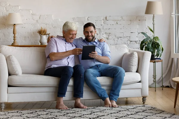 Glücklicher junger Mann und alter Vater mit digitalem Tablet. — Stockfoto