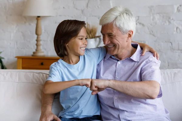 Happy preteen kid boy bumping fists with old grandfather. — Stock Photo, Image