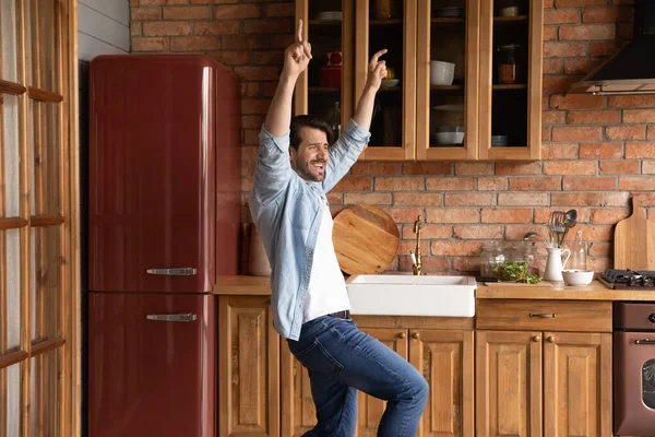 Overjoyed funky young man dancing in old fashioned kitchen. — Foto Stock