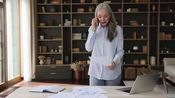 Anciana dama trabajo desde el hogar uso celular portátil papel documentos — Vídeo de stock