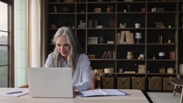 Dizüstü bilgisayarla yapılan yaşlı kadın çalışmaları çevrimiçi ders notları alıyor — Stok video