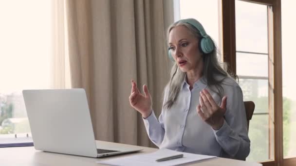 Old lady teacher consult pupil online talk using laptop headphones — 图库视频影像