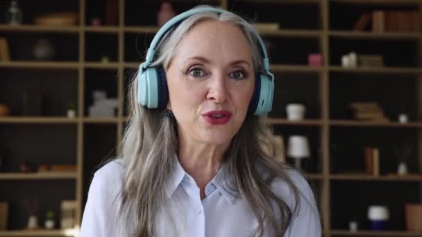 Retrato señora anciana profesora en auriculares interactúan con los alumnos en línea — Vídeo de stock