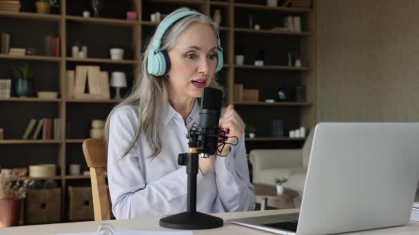 Senior female sit by laptop in earphones broadcast training live — Stockvideo