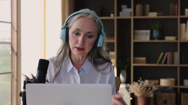 Mature female speaker in headset talk in microphone before laptop — Vídeo de Stock