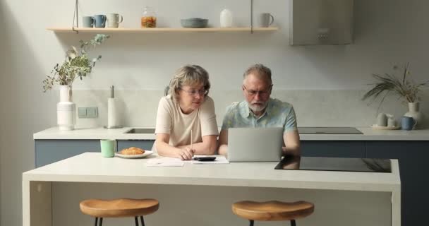 Serious older adult family couple manage domestic finances using laptop — Stockvideo
