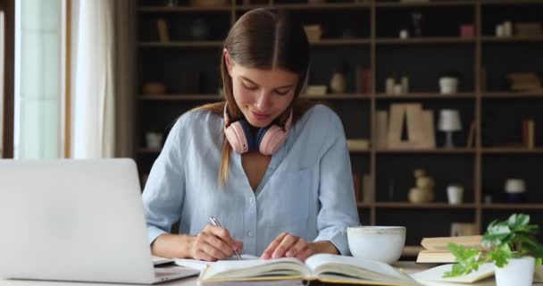 Estudiante que estudia usando el ordenador portátil, mira a través de la información en libros de texto — Vídeos de Stock