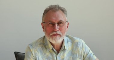 Gözlüklü yaşlı adam kameraya sağlıklı bir gülümsemeyle bak.