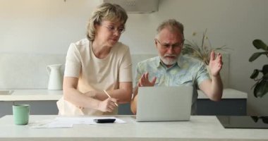 Emekli çift, aşırı harcamaktan rahatsız olan dizüstü bilgisayarla banka hesabını kontrol ediyor.