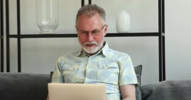 Aşırı sevinçli yaşlı dede dizüstü bilgisayara bak ve internetten ödül kazan.