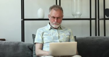 Dizüstü bilgisayarda konsantre olmuş yaşlı erkek yetenekli internet kullanıcısı işi