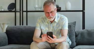 Mutlu olgun büyükbaba telefon ekranında iyi haberler okumaktan zevk alır.