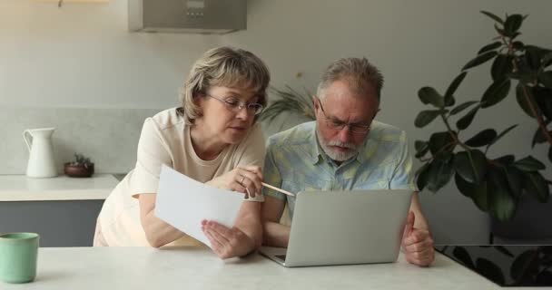 Serious senior adult couple focused on paperwork at home office — Vídeo de Stock