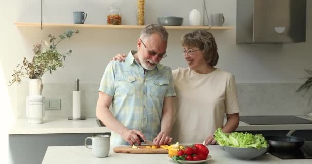 Śmiejąc się stary mąż siekać pieprz do sałatki słuchać żony — Wideo stockowe