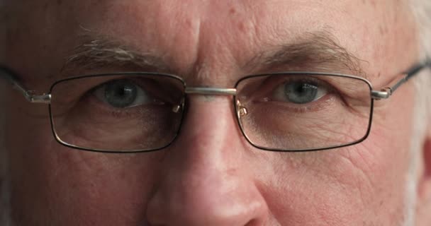 Grey eyes of elderly man looking at camera through glasses — 图库视频影像