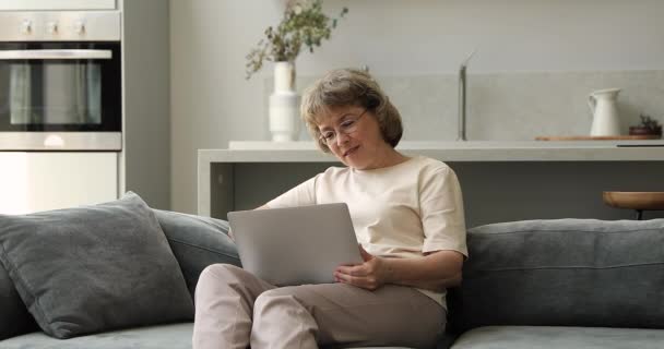 Relajado hembra mayor pasar tiempo en casa usando ordenador portátil pc — Vídeos de Stock