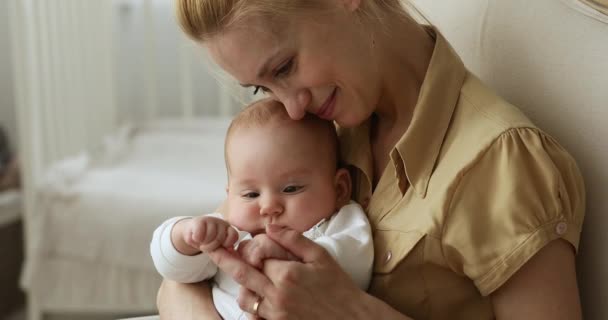 Anne kollarında oturan tatlı bir bebek. Annenin eliyle oynuyor. — Stok video