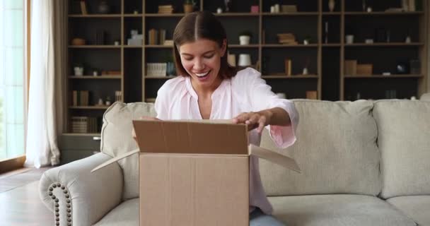 Woman opens received delivered parcel, with decoration items for house — Stock Video