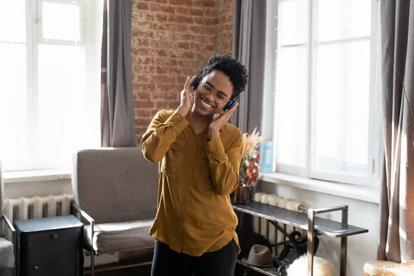 Glad ung afrikansk kvinna lyssnar musik i hörlurar. — Stockfoto