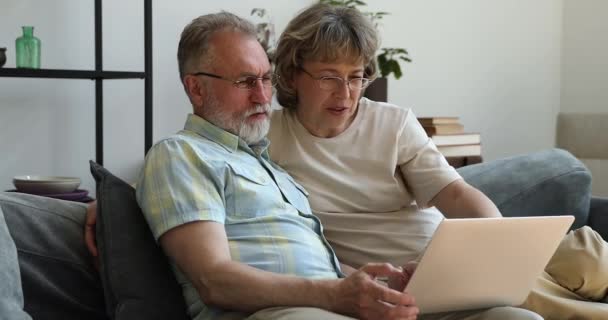 Lachende ältere Großeltern nutzen Unterhaltung-App auf modernem Laptop — Stockvideo