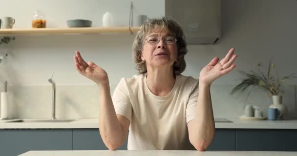 Happy old age granny座っていますにホームキッチン作るビデオコール — ストック動画