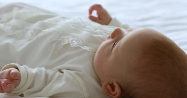 Bebek büyüyen aktif bir bebek yatakta uzanmış ellerini hareket ettiriyor. — Stok video