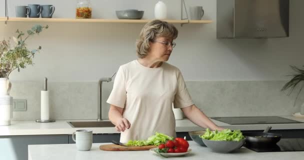 Gelukkig senior volwassen oma huisvrouw genieten van koken op moderne keuken — Stockvideo