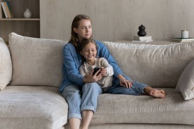 Küçük çocuk cep telefonu kullanırken annesi uzaklardan bakıyor..