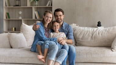 Sevgi dolu bir aile kanepede dinleniyor, kameraya bakıyor..