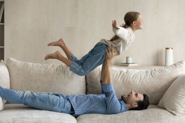 Neşeli genç baba havadaki küçük kızı kaldırıyor.