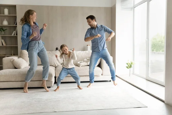 Joyful young couple parents and little kid dancing at home. — стоковое фото