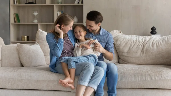 Gelukkig jong ouders kietelen klein kind dochter. — Stockfoto