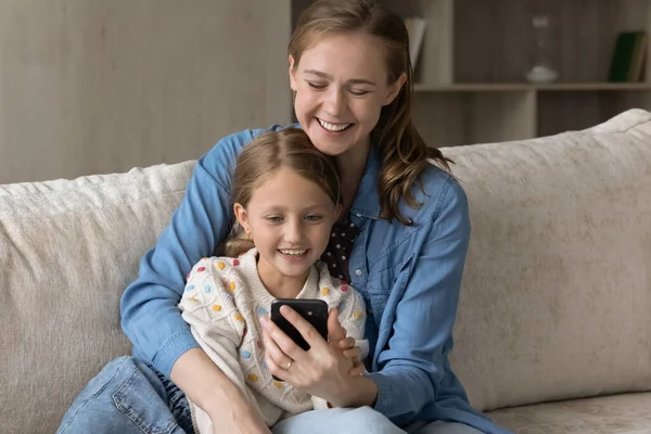 Happy bonding young mother and little daughter using cellphone. — Fotografia de Stock