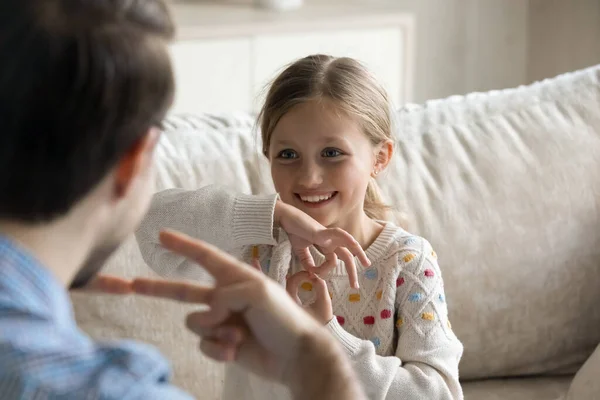 Bonne petite fille utilisant le langage des signes, communiquer avec le père. — Photo