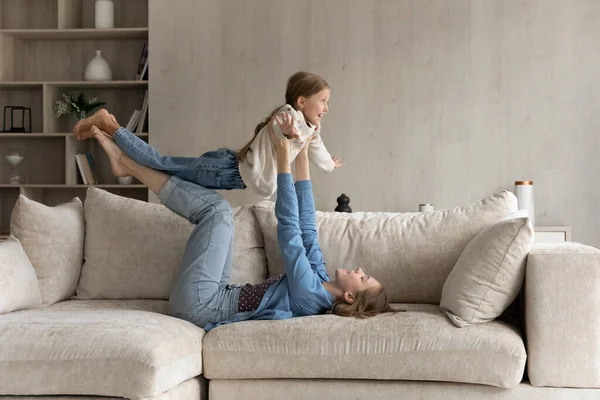 Gelukkige jonge moeder heffen in de lucht vreugdevolle kleine dochter. — Stockfoto