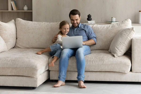 Zorgzame jonge vader en klein kind met behulp van laptop thuis. — Stockfoto
