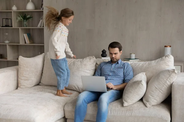 Concentrato giovane padre che lavora, mentre il bambino piccolo gioca. — Foto Stock